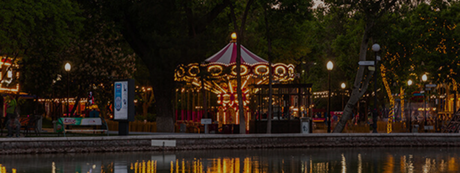 Evening park with carousel and festive lights in Central Park