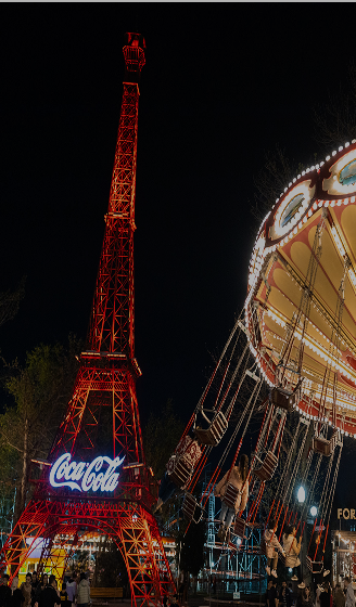 Glowing Coca-Cola tower and spinning carousel at night in Central Park